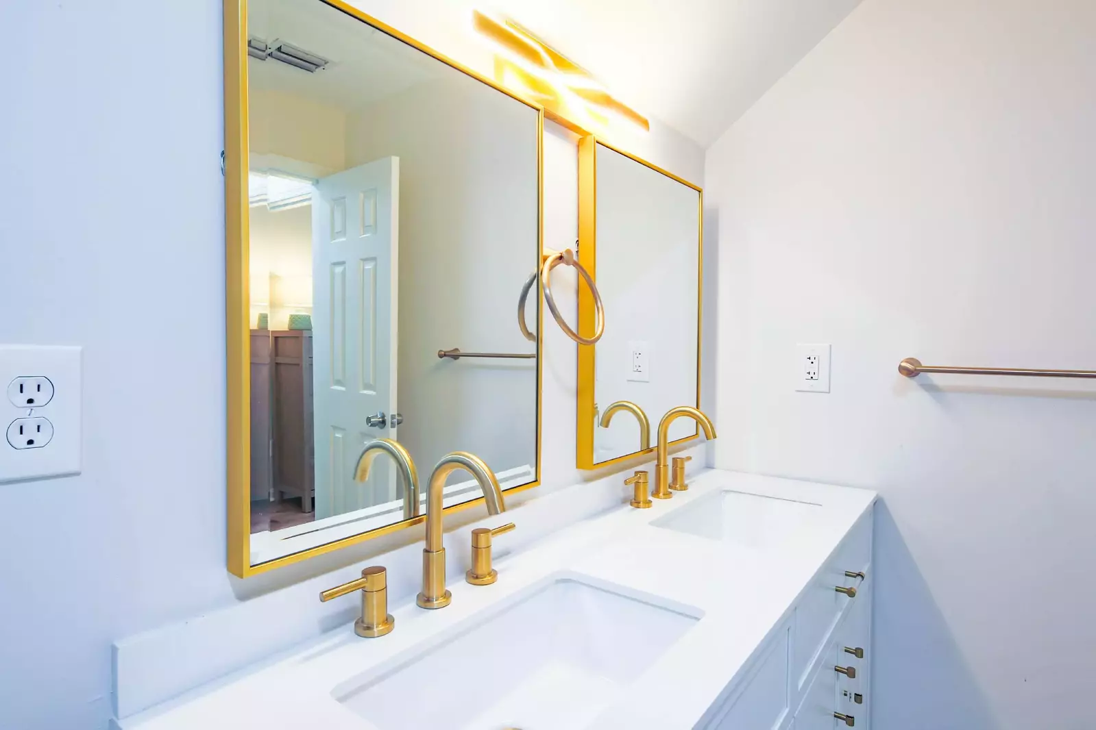 The bathroom features a dual-sink vanity with white cabinetry and gold hardware.