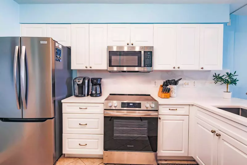 The kitchen features a refrigerator, electric range, microwave, keurig and drip coffee maker.