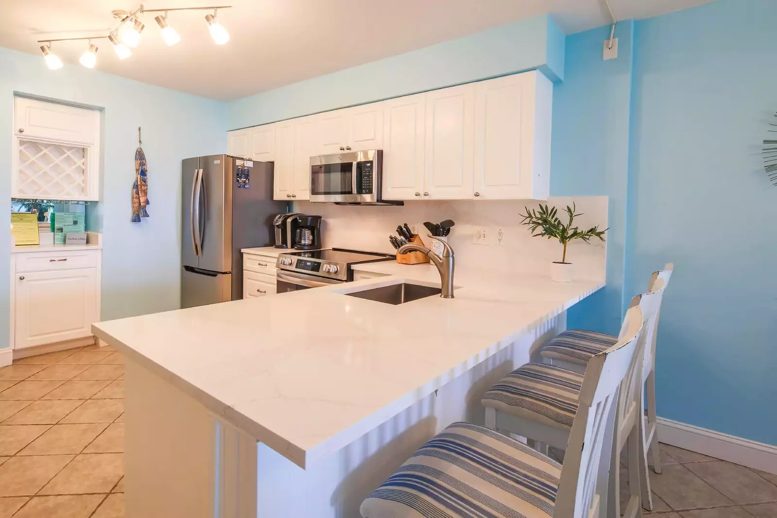 There are three stools alongside the kitchen's quartz countertop.