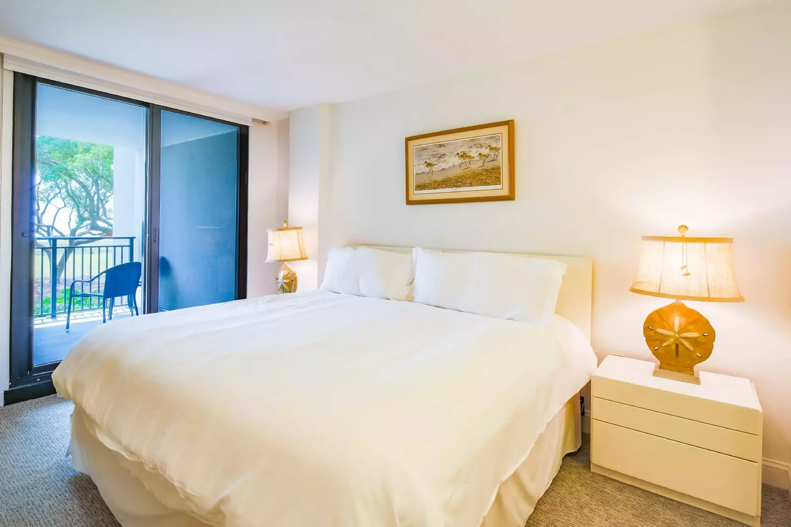 The master suite features a king bed, night stands with reading lamps and access to the balcony.