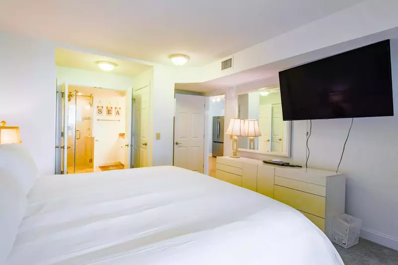 The master suite also features a wall-mounted smart TV, a dresser and mirror.