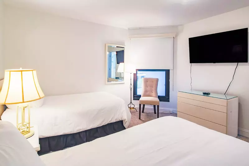 There is a wall-mounted smart TV and dresser in the guest bedroom.