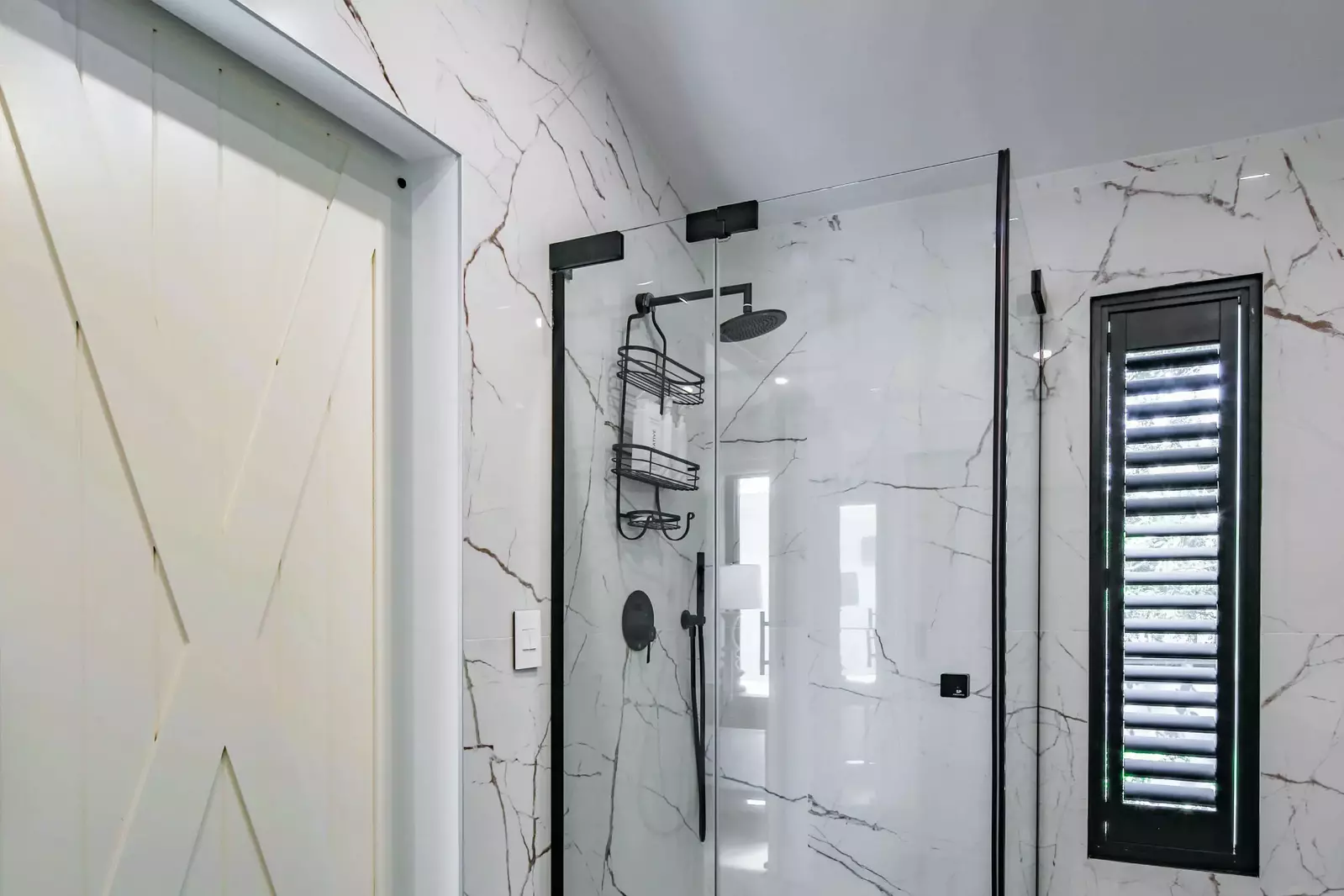 The en suite bathroom also features a walk-in shower and porcelain tiled walls.