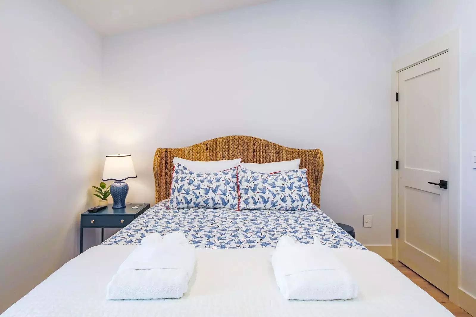 This guest bedroom features a queen bed, night stand with reading lamp and a closet.