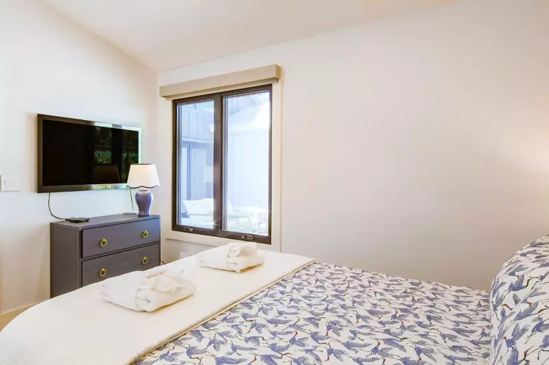 This guest bedroom also features a dresser and wall-mounted smart TV.