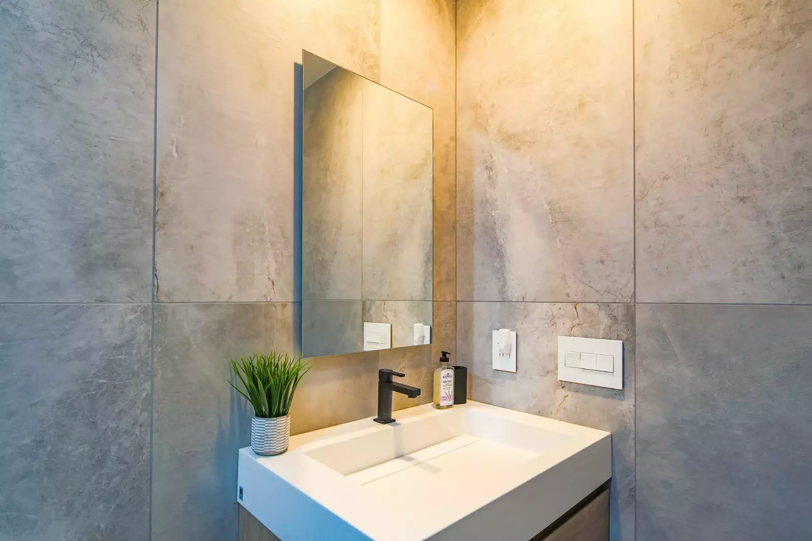 This hallway bathroom features a beautiful vanity and stone walls.