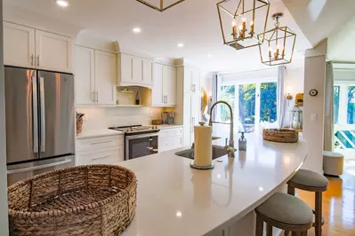 The kitchen has a tiled backsplash, designer light fixtures and gorgeous cabinetry.