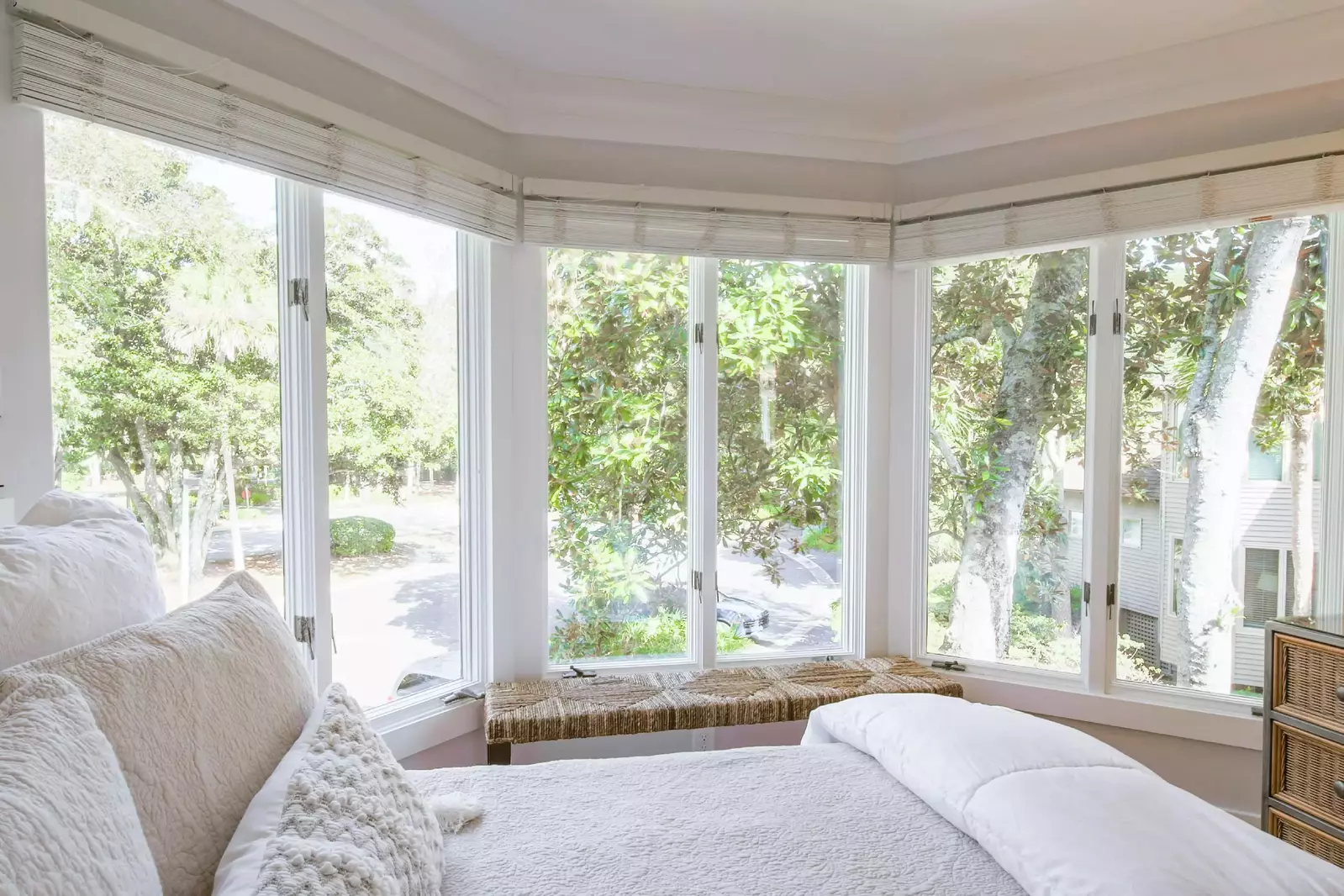 There is a bench and dresser near the wall of windows in the guest bedroom.