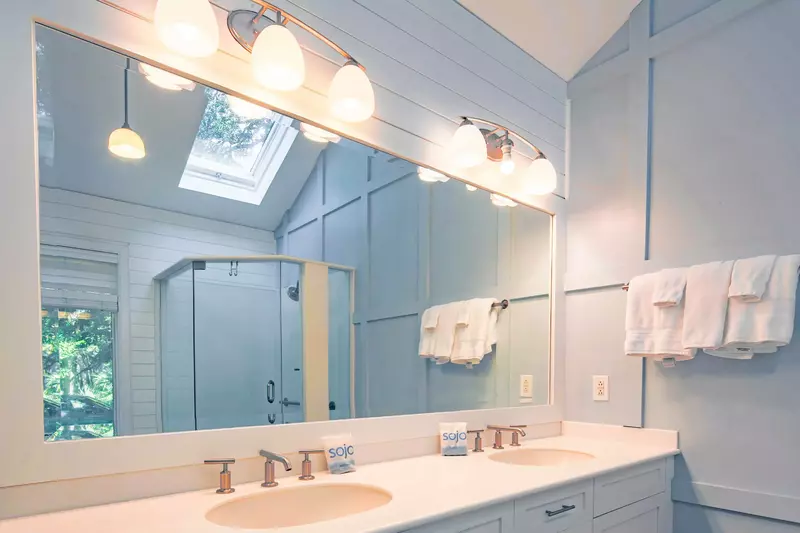 The master bathroom features a dual sink vanity, vaulted ceilings and shiplap walls.