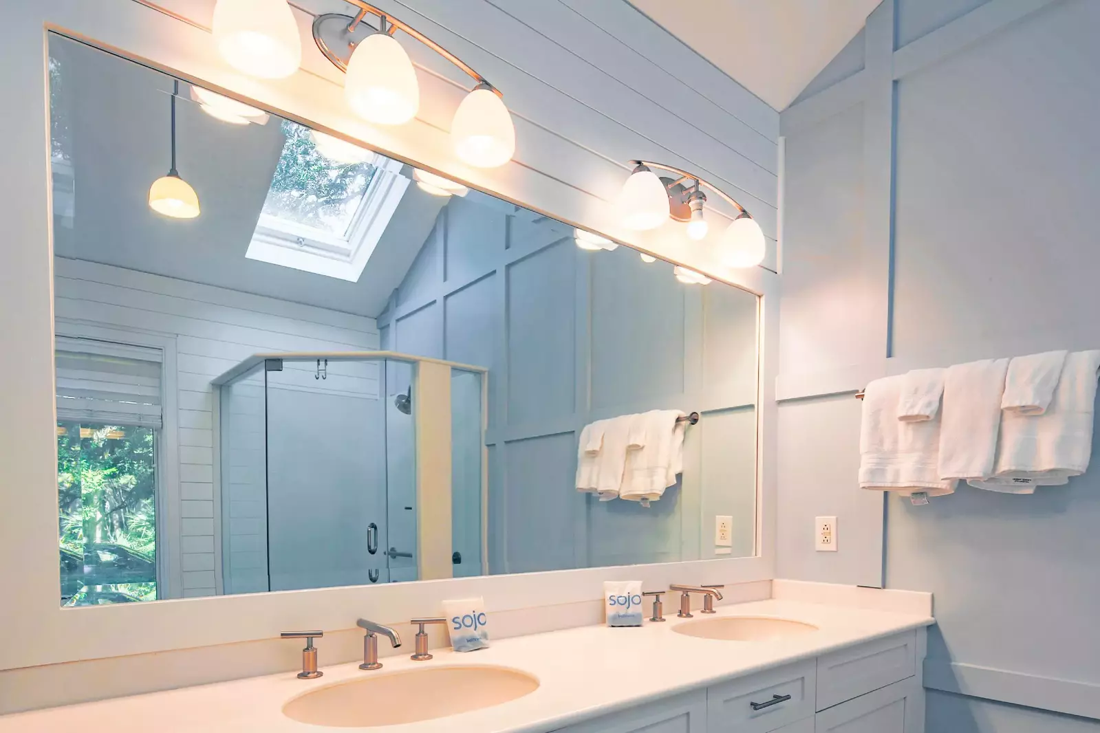 The master bathroom features a dual sink vanity, vaulted ceilings and shiplap walls.