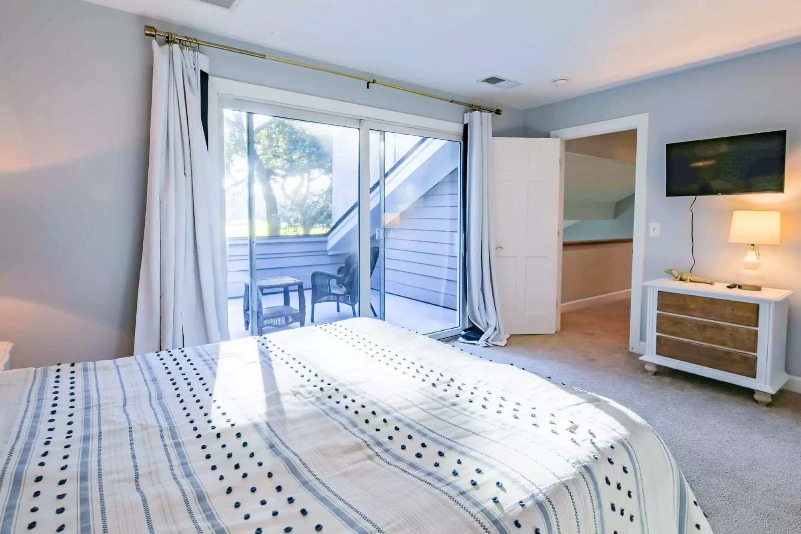The queen suite also has a dresser, wall-mounted smart TV and a private deck with outdoor seating area.
