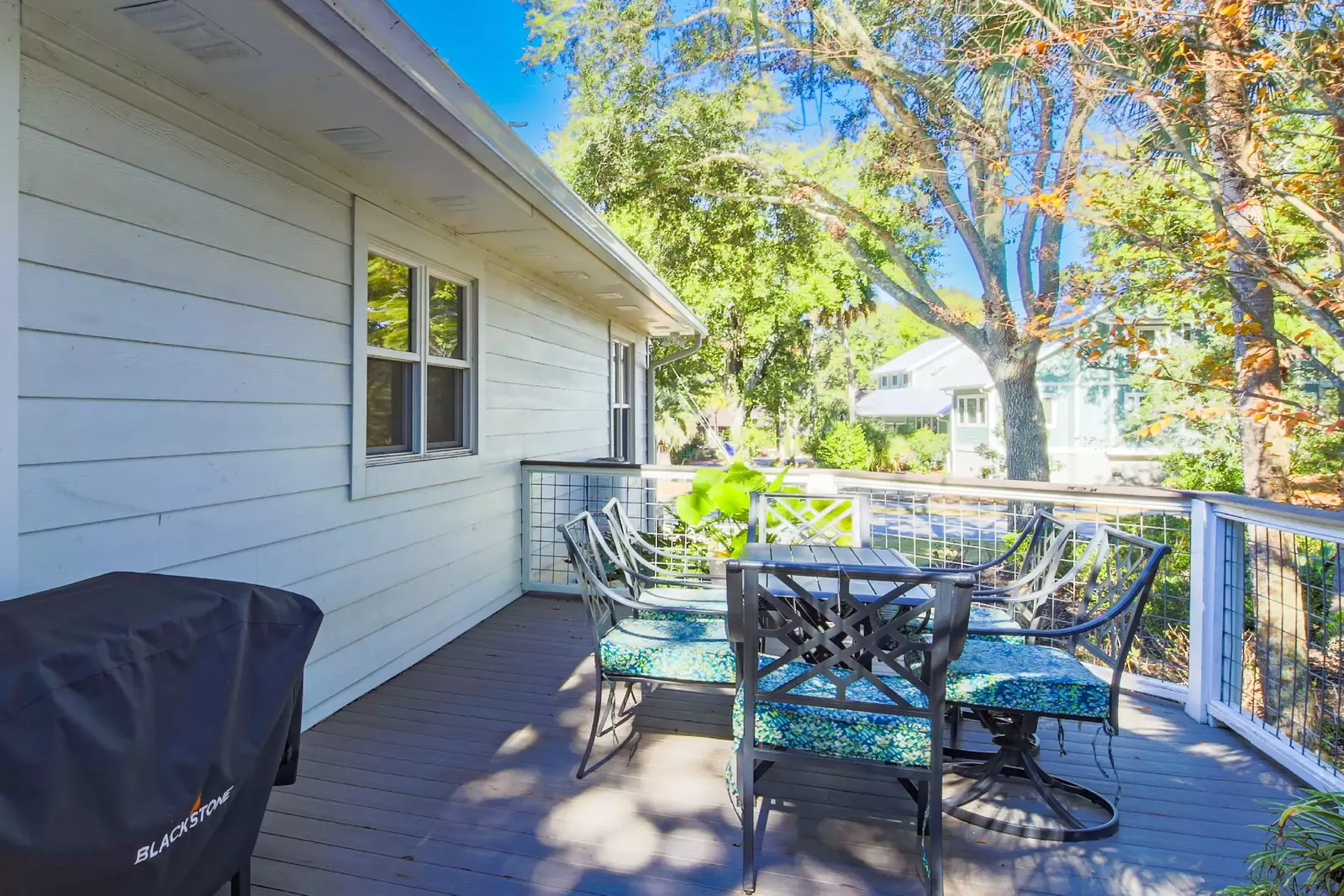 The screened porch connects to the side deck, which has a gas grill and outdoor dining table.