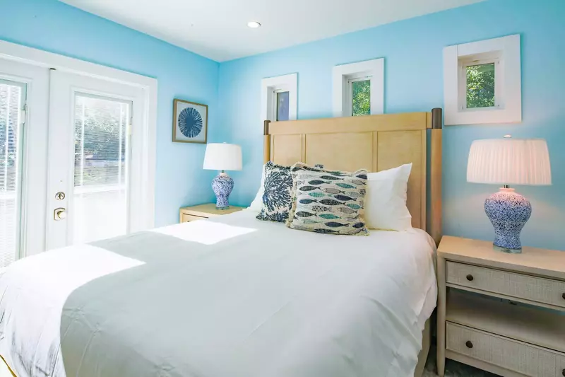 The sun-drenched primary suite features a queen bed and night stands with reading lamps.