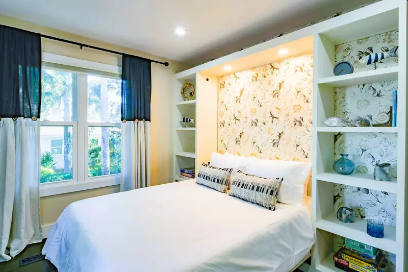 This guest bedroom features a queen bed with bookshelves.