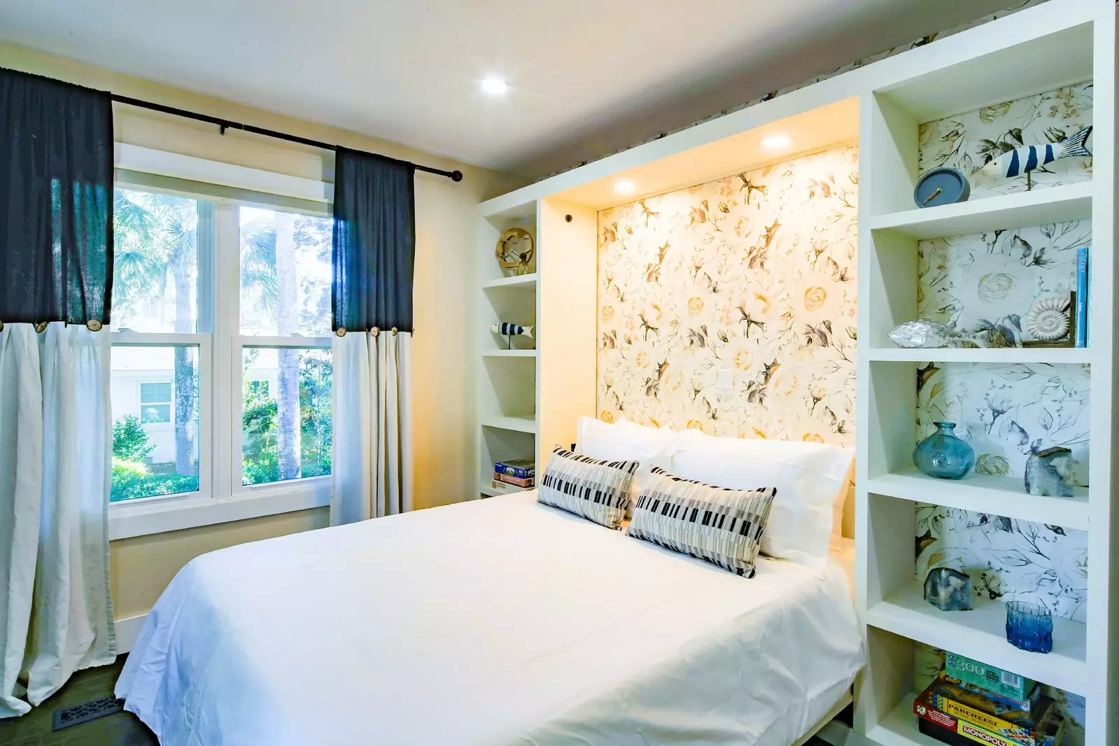 This guest bedroom features a queen bed with bookshelves.