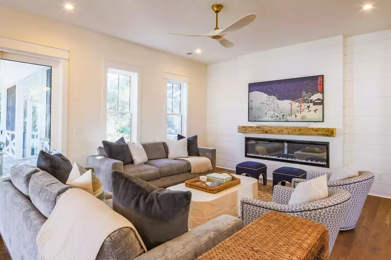 The living room features two sofas, two arm chairs and a wall-mounted smart TV.