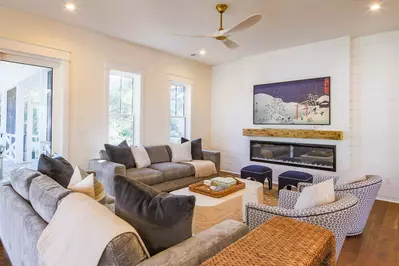 The living room features two sofas, two arm chairs and a wall-mounted smart TV.