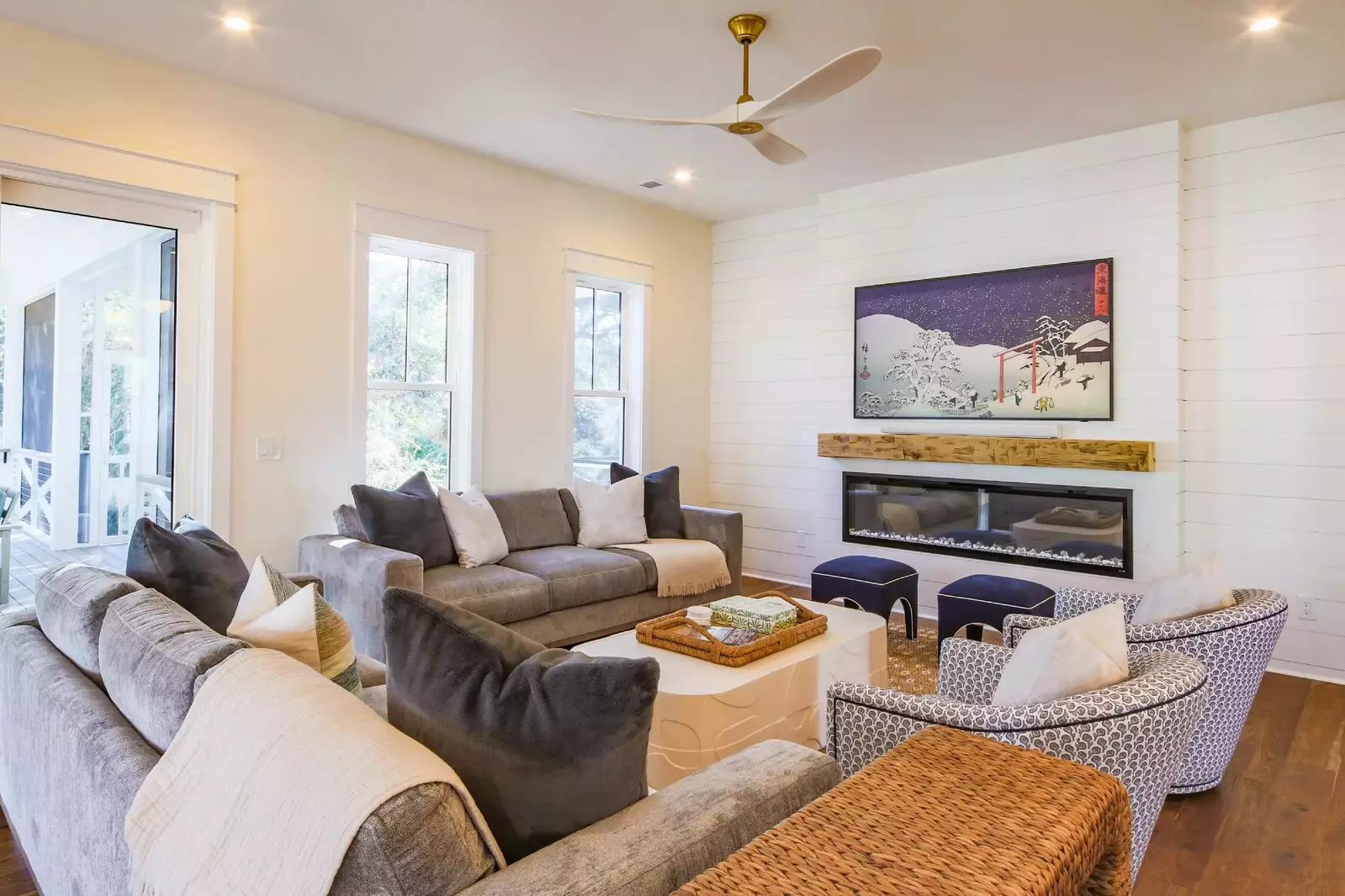 The living room features two sofas, two arm chairs and a wall-mounted smart TV.