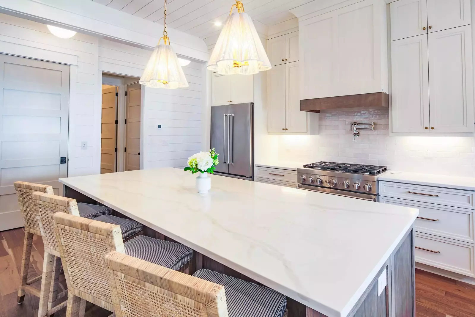 The kitchen features a central island with four stools.