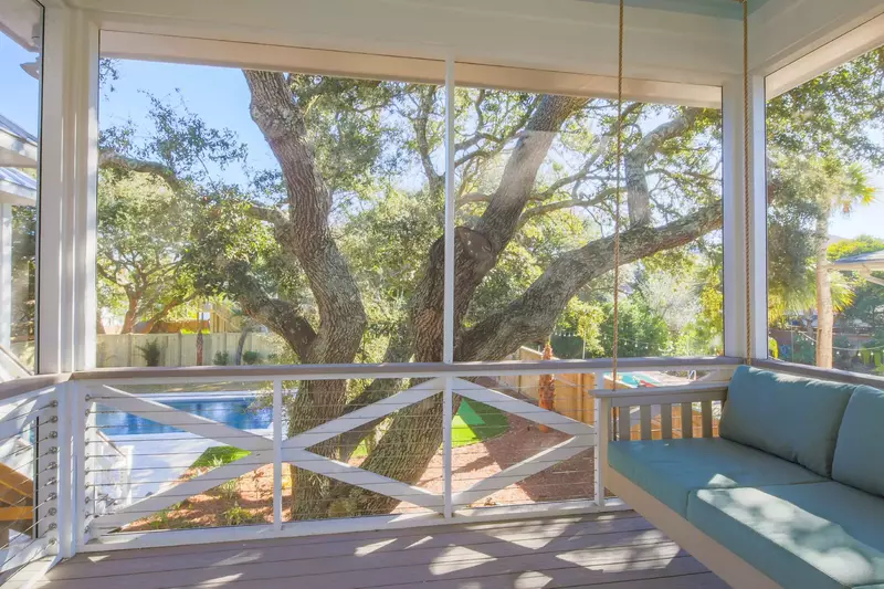 The swing on the private balcony off of the primary suite overlooks the pool and live oak tree.