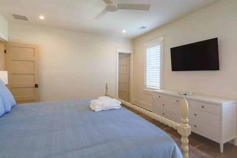 The upstairs guest bedroom also has a dresser, wall-mounted TV and ceiling fan.