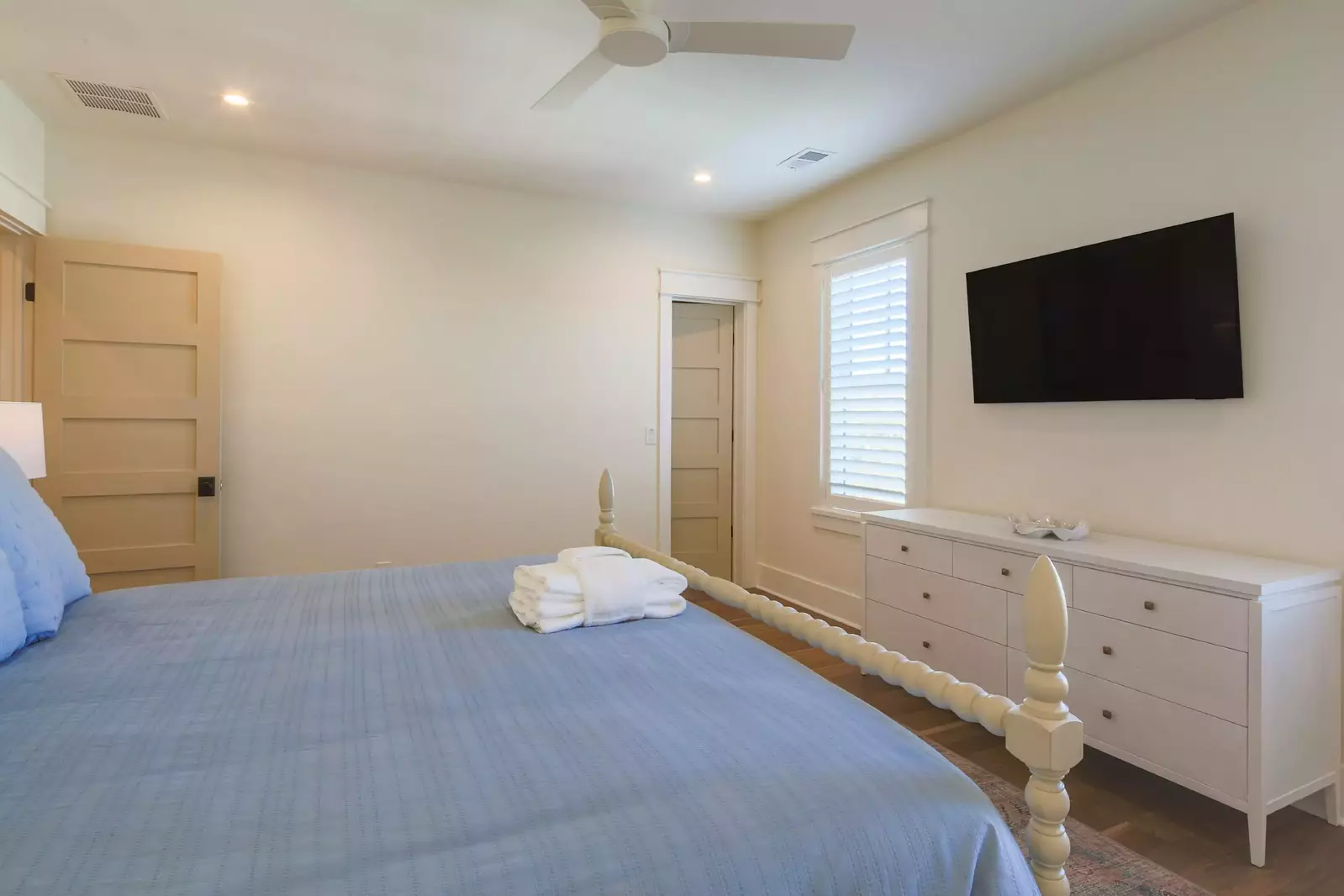 The upstairs guest bedroom also has a dresser, wall-mounted TV and ceiling fan.