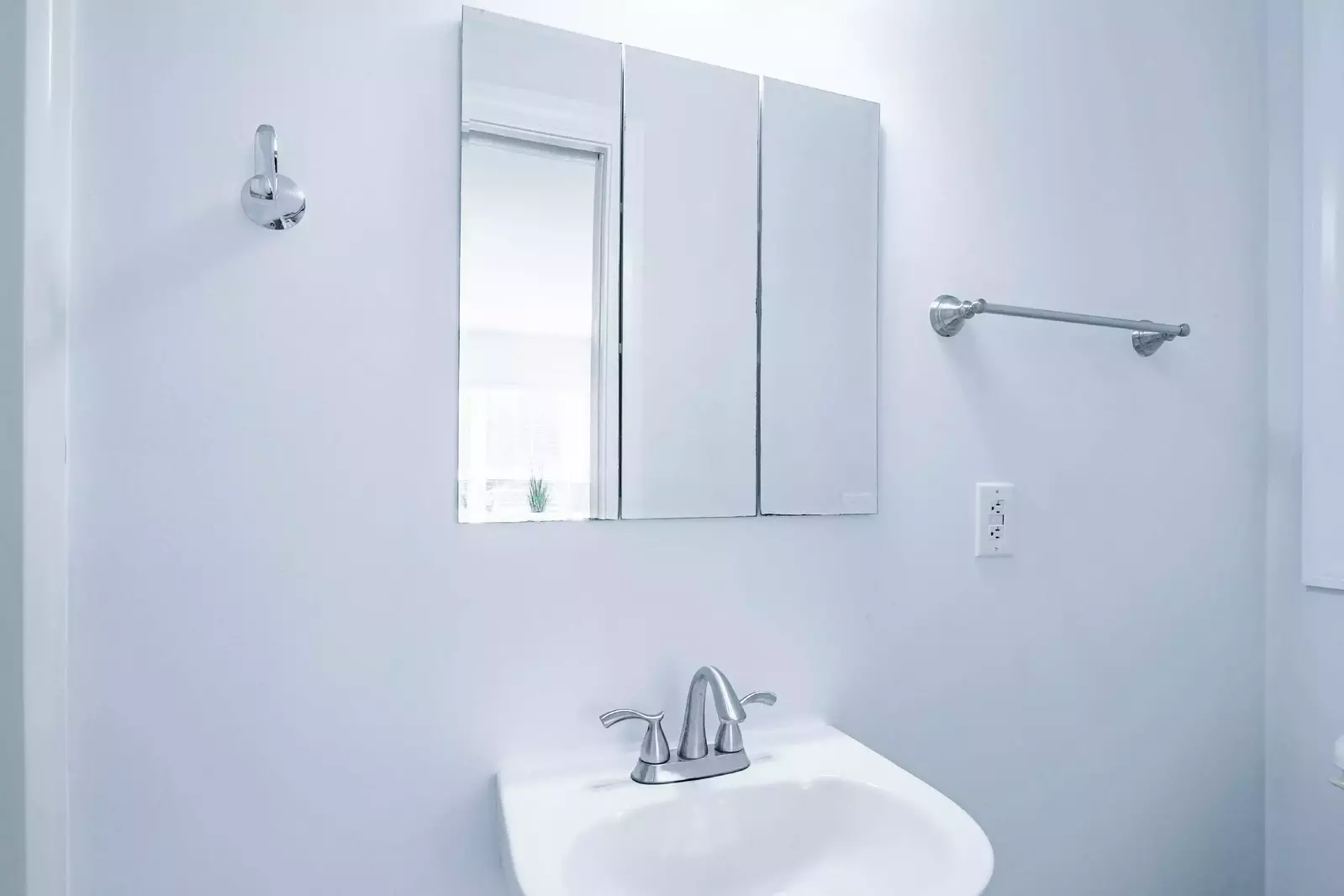 The en suite bathroom features a pedestal sink and a medicine cabinet.