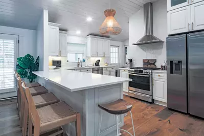 The kitchen features counter seating, white cabinetry and stainless steel appliances.