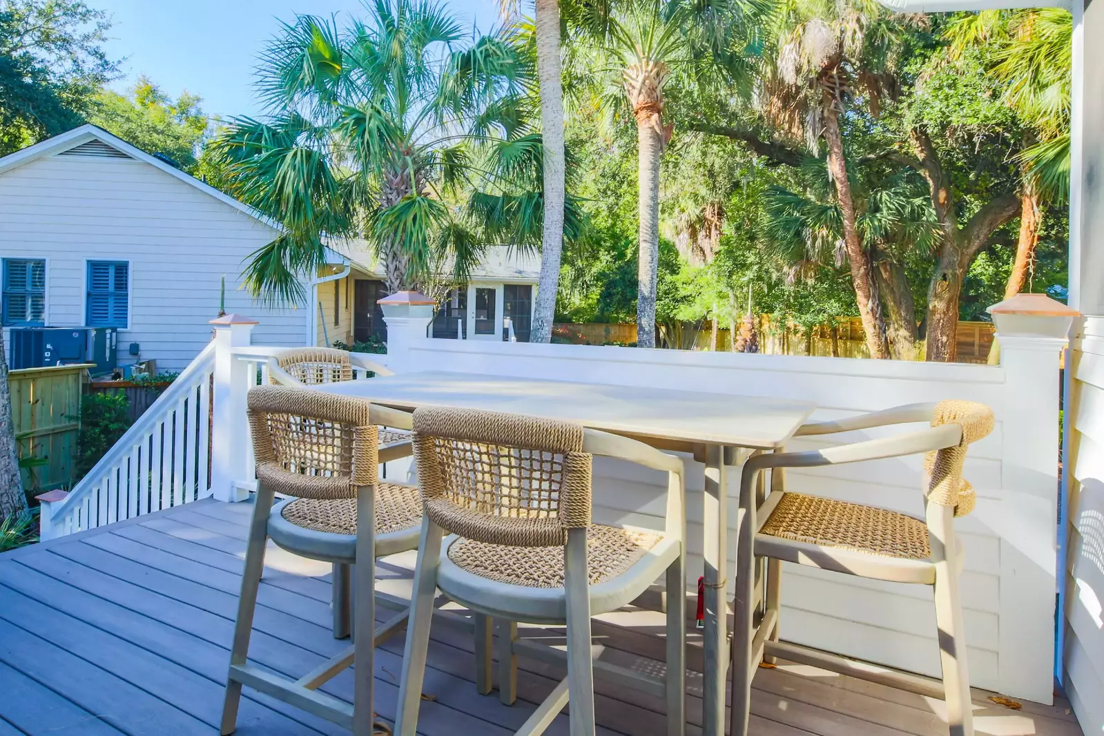 The back deck has an outdoor dining table and a staircase down to the pool area.