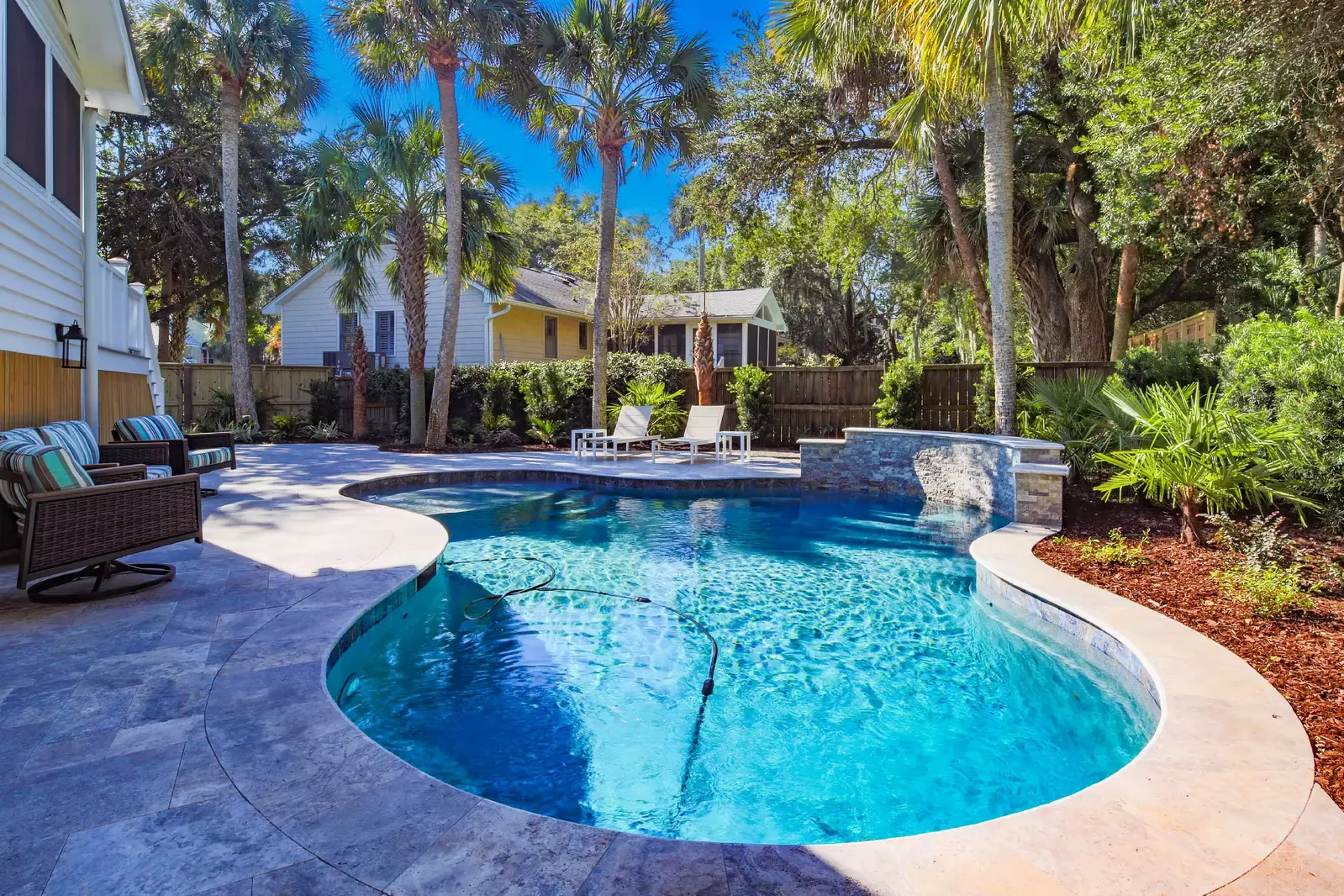 The backyard features an incredible tropical oasis with a private pool and outdoor seating.