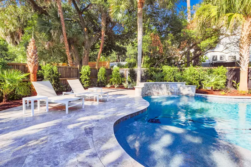 The pool deck is surrounded with palm trees. live oaks and other lush Lowcountry tropical plants.