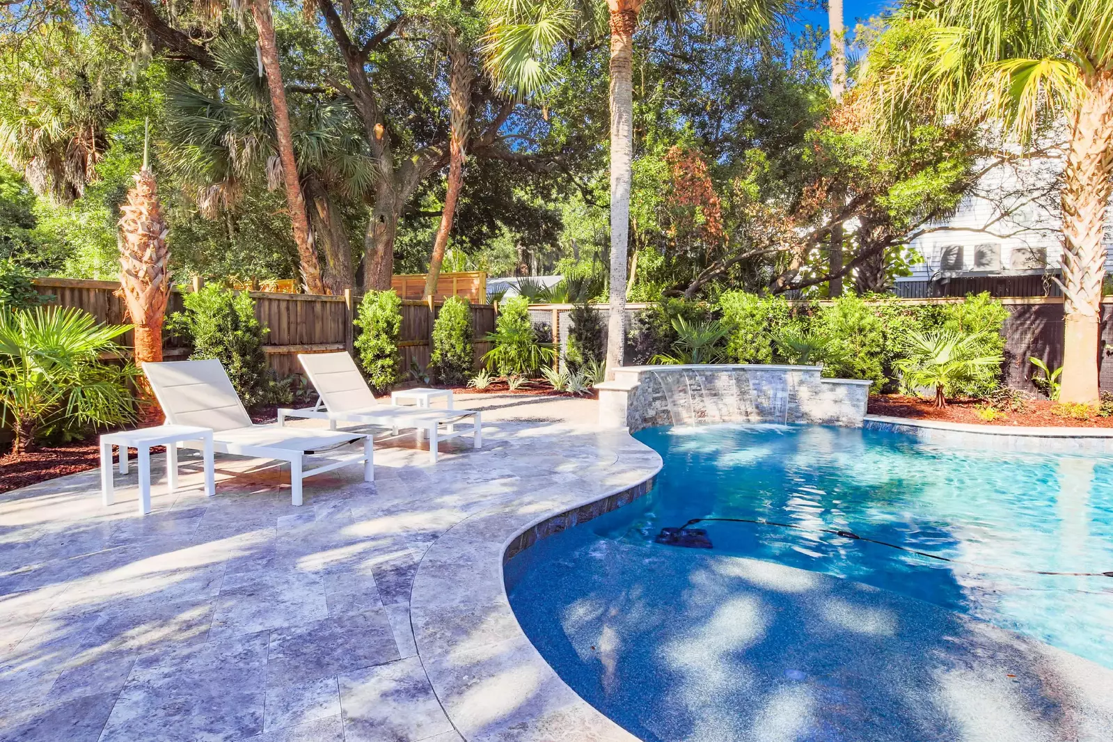 The pool deck is surrounded with palm trees. live oaks and other lush Lowcountry tropical plants.