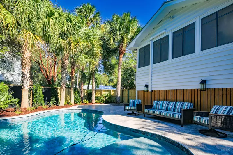There is an outdoor sofa and arm chairs on the pool patio alongside the house.