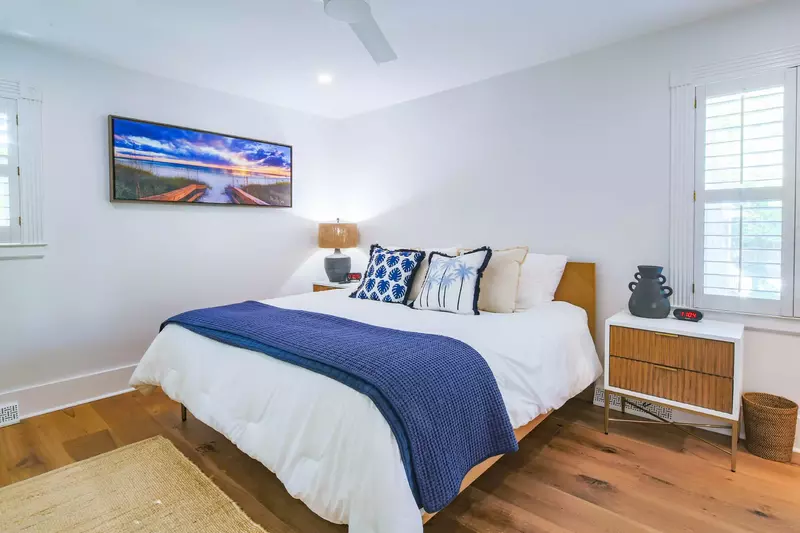 The second master suite features a king bed, ceiling fan and night stands.