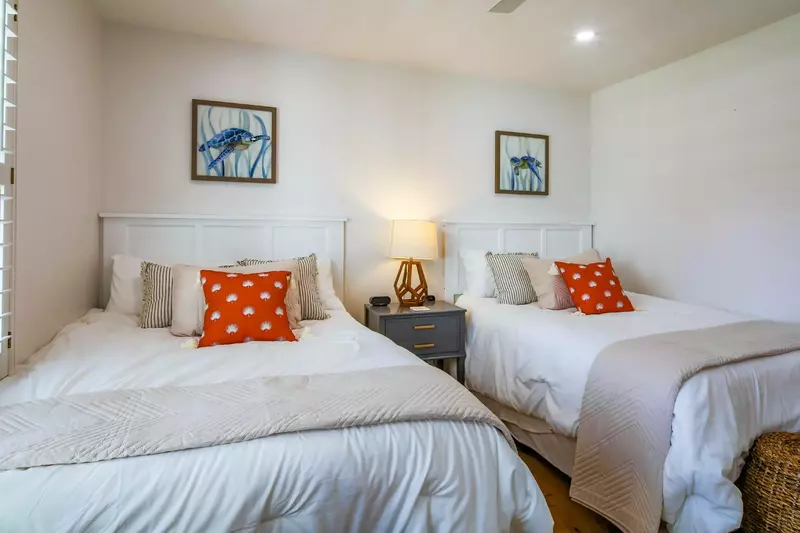 The queen bedroom features two queen beds and a night stand with reading lamp.