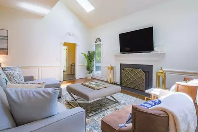 The central living room features vaulted ceilings, a wall-mounted TV, sky lights and hardwood floors.