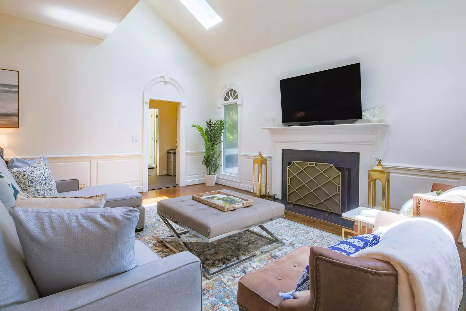 The central living room features vaulted ceilings, a wall-mounted TV, sky lights and hardwood floors.