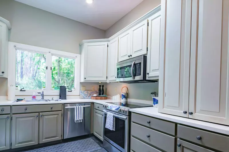 The kitchen features stainless steel appliances, vaulted ceilings and a large picture window above the sink.