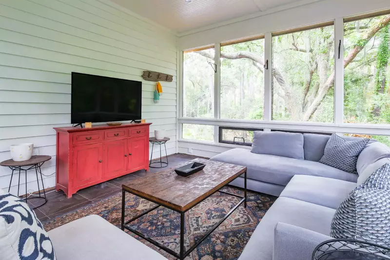 The sunroom featues a large sectional, a large screen TV and views of the gorgeous maritime forest.