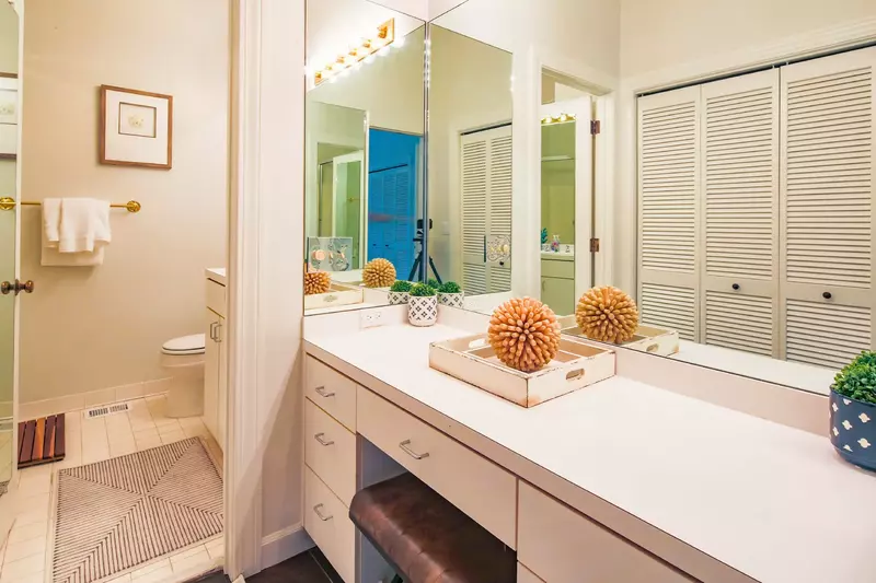 This en suite bathroom features a spacious makeup vanity and closet area.