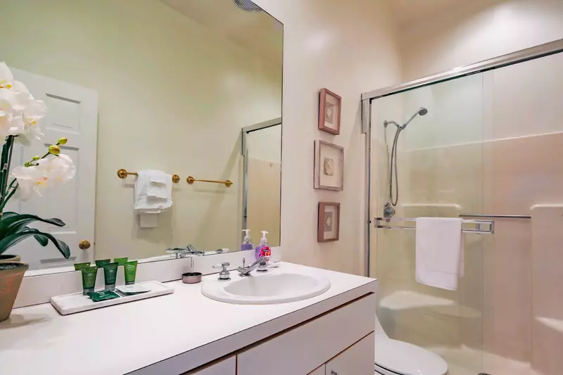 This hallway bathroom with a spacious vanity and walk-in shower is shared by two guest bedrooms.