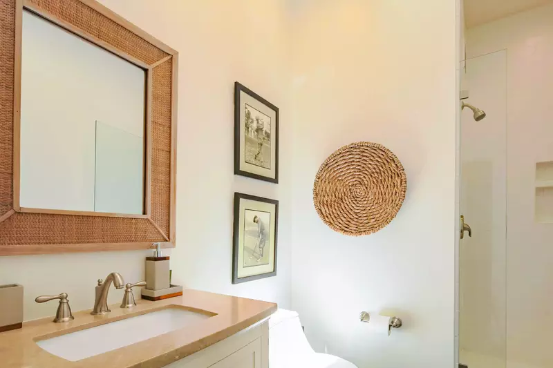 This bathroom with a vanity and a tiled, walk-in shower is located near the kitchen and sunroom.