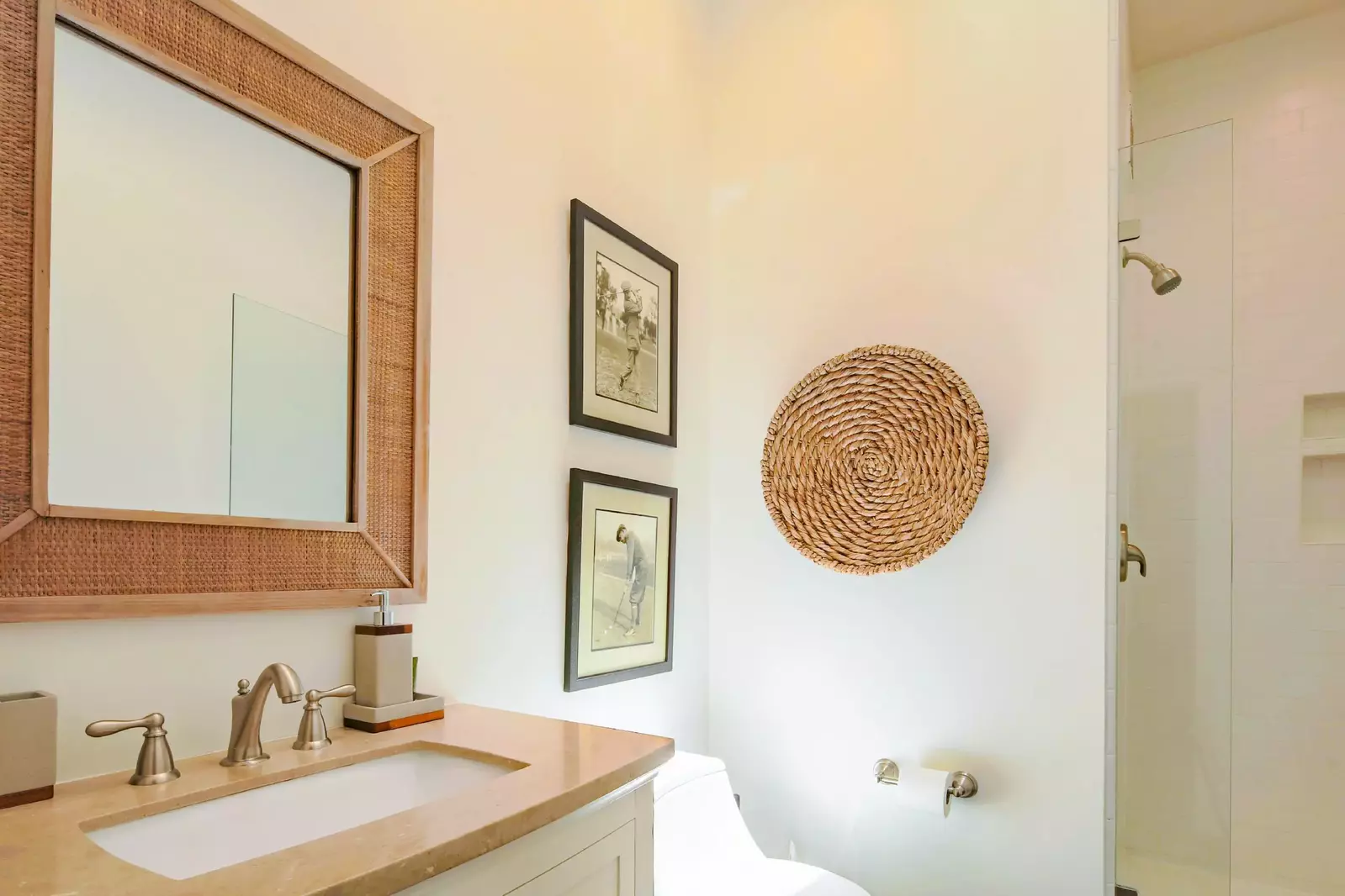 This bathroom with a vanity and a tiled, walk-in shower is located near the kitchen and sunroom.