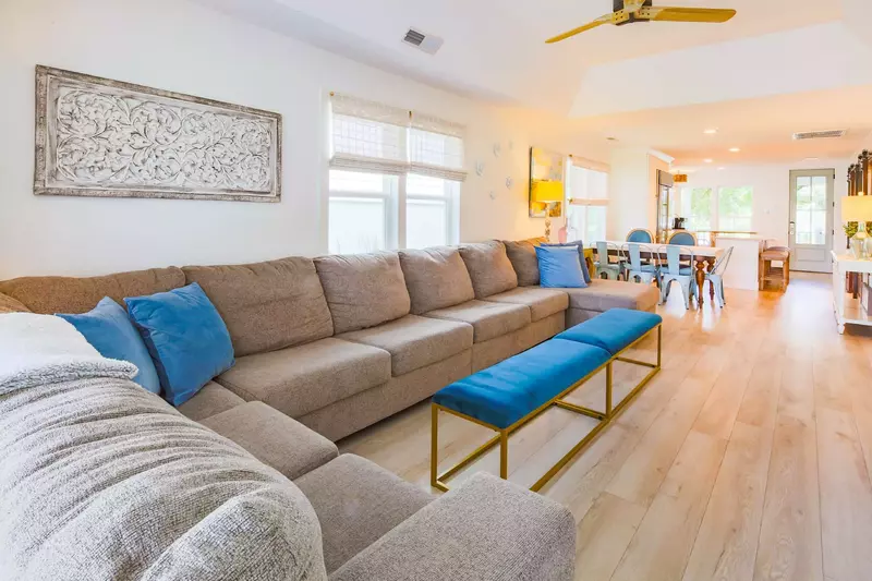 The living room features a tray ceilng, expansive sectional sofa and ceiling fan.