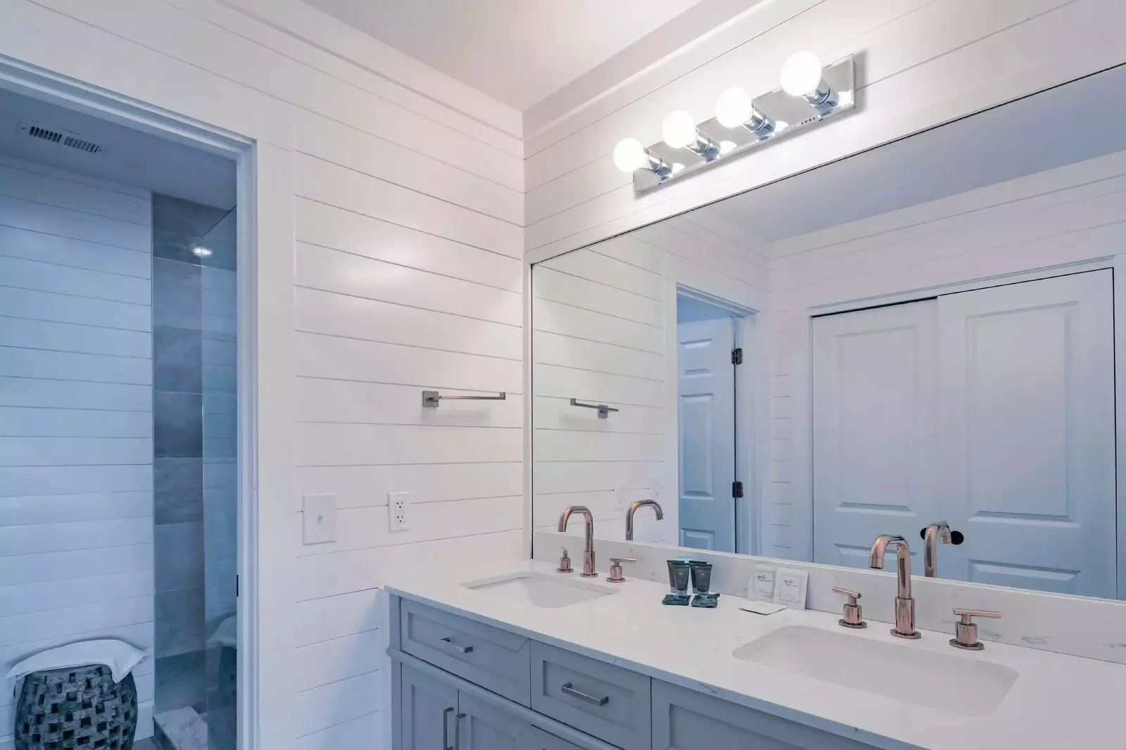 The en suite bathroom features a dual sink vanity and shiplapped walls.