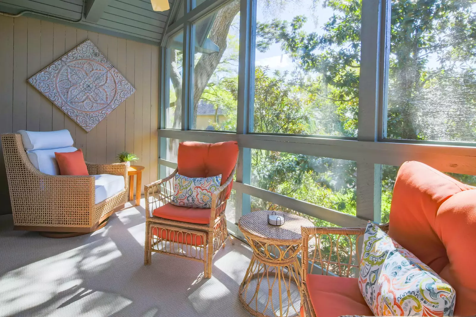 There are three cushioned arm chairs and two end tables on the screened porch.