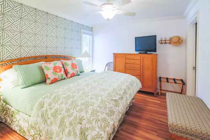 The bedroom features a king bed, dresser, bench and streaming TV.