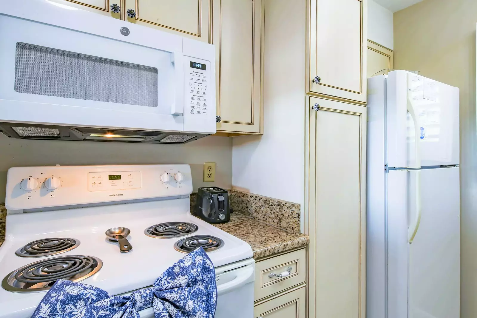 The refrigerator is located near the range and microwave.
