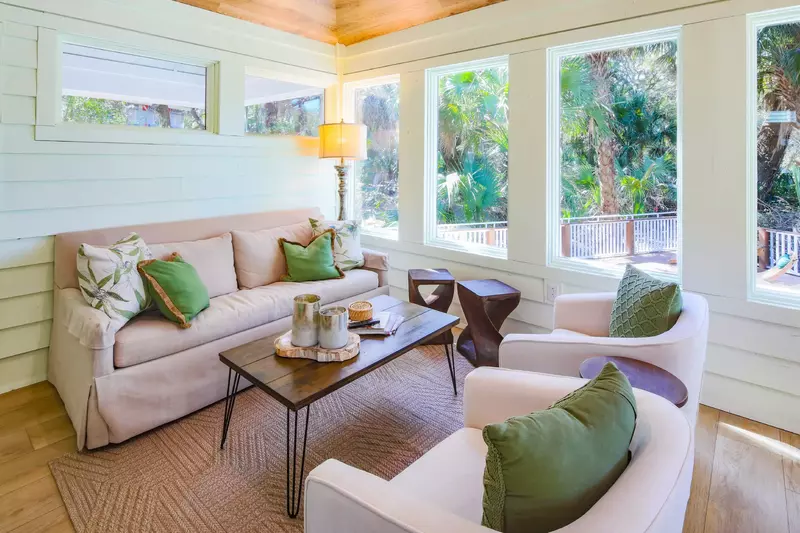The sunroom features a comfortable seating area and views of the private pool & deck.