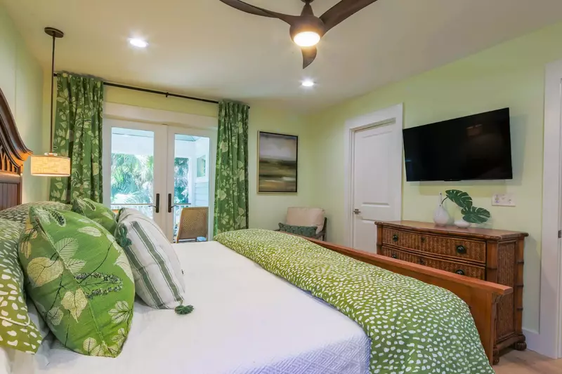 The master suite also features a dresser, wall-mounted smart TV, ceiling fan and en suite bathroom.